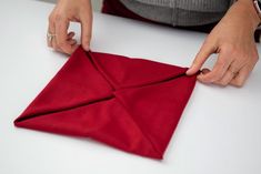 a woman is cutting up a red piece of cloth