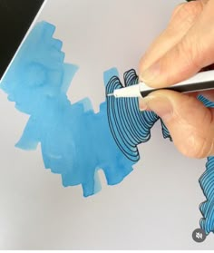 a person is using a marker to draw something on the paper with blue and black ink