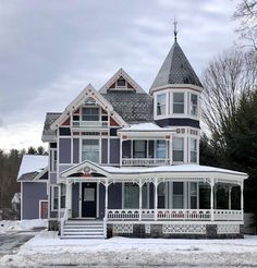 a large victorian style house with snow on the ground