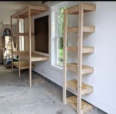 an unfinished room with shelves and ladders next to a window