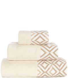 four towels stacked on top of each other in white and beige colors with geometric designs