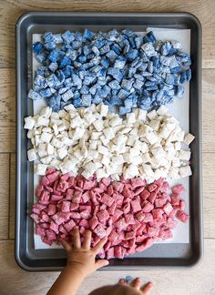 a toddler reaching for blue and red dog treats on a tray