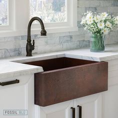 a kitchen sink sitting under a window next to a faucet and counter top