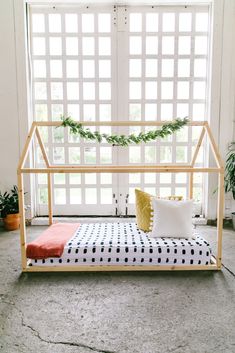 a bed that is in front of a window with some plants on the wall behind it