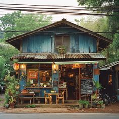 an old wooden building with blue shutters on the front and windows is surrounded by greenery