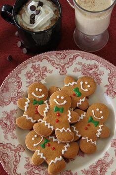 several gingerbread cookies on a plate next to a cup of hot cocoa and whipped cream