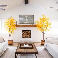 a living room with white furniture and yellow trees