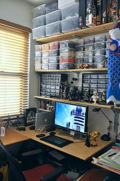 a desk with a computer on top of it in front of shelves filled with toys