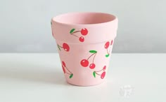 a pink cup with cherries painted on the outside and inside, sitting on a white surface