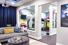 a living room filled with furniture next to a gym equipment set up on top of a hard wood floor