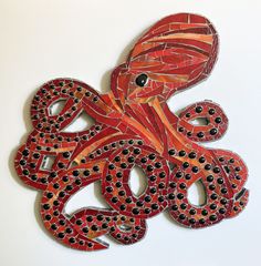 an octopus made out of red and black beads on a white surface with the word go written in it