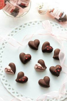 chocolates in the shape of hearts on a white plate with pink ribbon around them