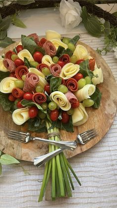 a bouquet of flowers on a wooden plate with silverware and forks next to it