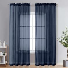 a blue curtain hanging on the side of a window next to a potted plant