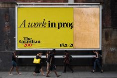 people walking past a large advertisement on the side of a building