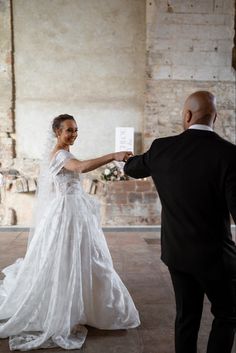 a bride and groom holding hands in an old building with exposed brick walls on either side