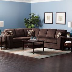 a living room with blue walls and brown furniture on the floor, including a sectional couch