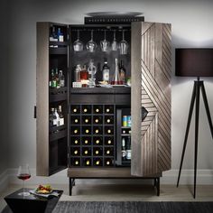 a cabinet with wine glasses and bottles in it next to a lamp on a table