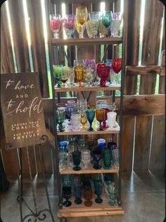 a display case filled with lots of different colored glassware on top of a wooden shelf