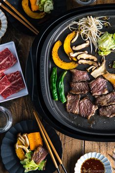 steak and vegetables on a grill with chopsticks