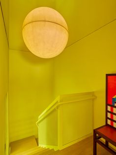 a room with yellow walls and a red bench in front of a round light fixture