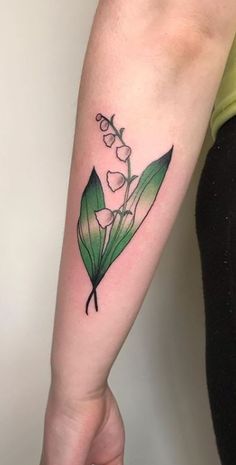 a woman with a tattoo on her arm holding a flower in her left hand and wearing a green t - shirt