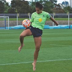 a woman kicking a soccer ball on top of a field