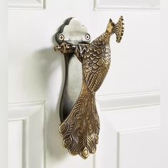 an ornate brass peacock door handle on a white door