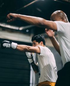 two men in white shirts and yellow shorts practicing boxing