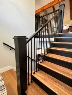 a staircase with black railing and wooden handrails