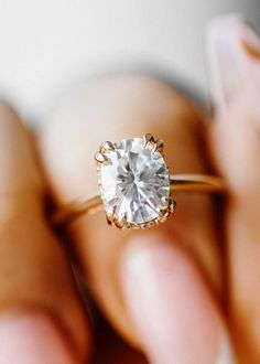 a close up of a person holding a ring with a diamond in it's center