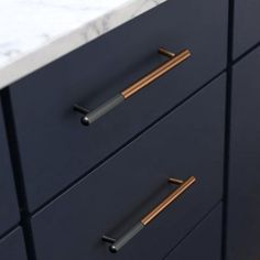 a bathroom vanity with marble counter top and brass handles on the drawer pulls in front of it