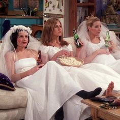 three brides sitting on a couch eating pizza and drinking beer