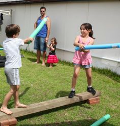 two young children playing baseball with adults in the back yard and one child holding a bat