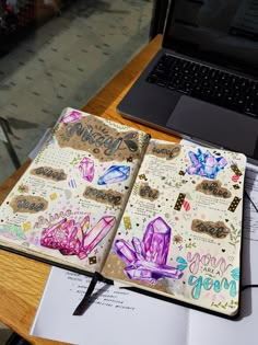 an open notebook sitting on top of a desk next to a laptop