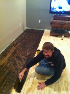 a man kneeling on the floor in front of a tv