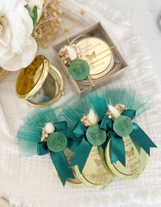 two green and white flowers sitting on top of a table next to some gold rings