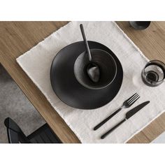 the table is set with utensils and a black bowl on top of it