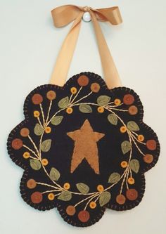 a black and brown decoration with a star on the front, surrounded by leaves and berries