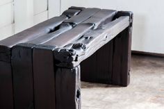 two wooden benches sitting next to each other on cement floored area with white wall in background