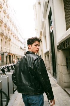 a man walking down the street in a leather jacket