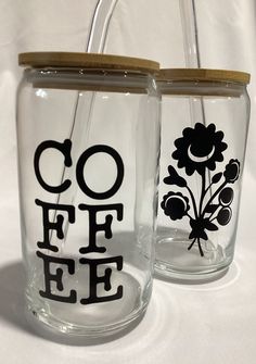 two glass jars with the words coffee and flowers painted on them are sitting on a white tablecloth