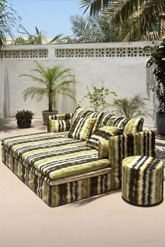 a couch sitting on top of a patio next to a potted plant and palm tree