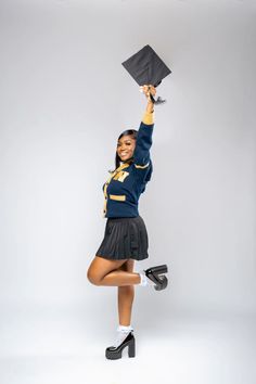 a woman in uniform is holding up a graduation cap and posing for the camera with her legs crossed