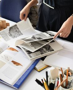 an open book sitting on top of a table next to a person's hand