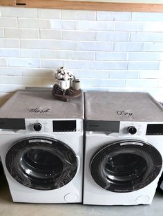 two washing machines sitting side by side in front of a white brick wall and floor