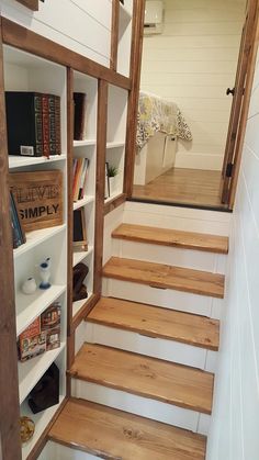 there is a book shelf with books on it and some stairs leading up to the second floor