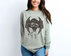 Please scroll down and continue reading   Cute Whimsigoth Gothic Bat Pair Love Long Sleeve TShirt Gothic Vampire Dark Goblincore Goth Long Sleeved Shirt Night Witchy Top Dark Academia Shirt Woman Gift Trendy               Elevate your wardrobe with our vintage-inspired unisex long sleeve t-shirt featuring an art nouveau illustration of two bats. This shirt blends Gothic allure with dark academia sophistication, allowing you to embody your goblincore aesthetic with ease. - 100% Cotton every Color Cotton Gothic Tops For Fall, Long Sleeve Tops For Halloween Alternative Fashion, Long Sleeve Tops For Halloween In Alternative Fashion, Halloween Long Sleeve Tops For Alternative Fashion, Gothic Cotton Tops For Fall, Goblincore Long Sleeve Tops For Fall, Long Sleeve Goblincore Tops For Fall, Alternative Style Long Sleeve Halloween Top, Alternative Long Sleeve Halloween Tops