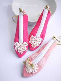 two pink purses with flowers on them sitting next to a white bowl