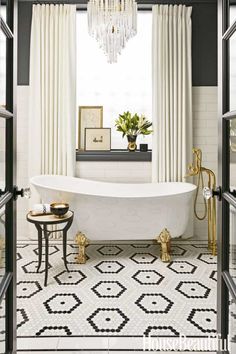 a white bath tub sitting under a window next to a black and white tiled floor